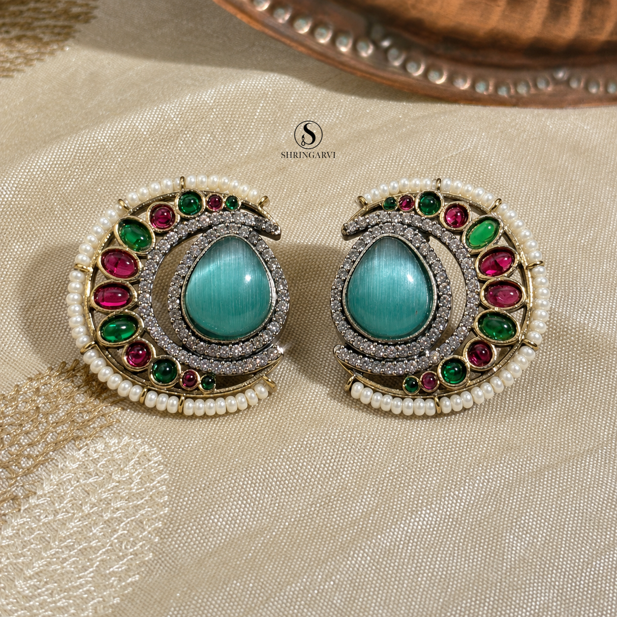 Aqua Blue Nisha oxidised brass studs with an aqua blue Monalisa stone, moissanite, AD stones, pearl border, and green and pink accent stones by Shringarvi.