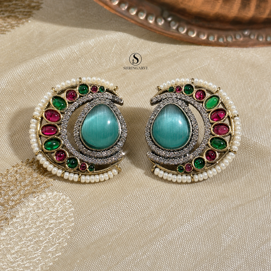 Aqua Blue Nisha oxidised brass studs with an aqua blue Monalisa stone, moissanite, AD stones, pearl border, and green and pink accent stones by Shringarvi.