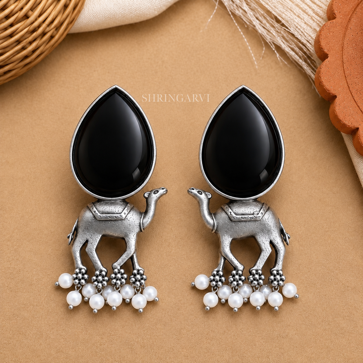 Handcrafted Black Monalisa Camel Danglers in oxidised brass featuring glossy black Monalisa stones, detailed camel motifs, and pearl drop accents for festive and ethnic styling.