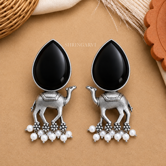 Handcrafted Black Monalisa Camel Danglers in oxidised brass featuring glossy black Monalisa stones, detailed camel motifs, and pearl drop accents for festive and ethnic styling.
