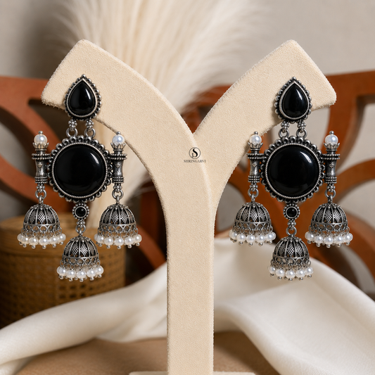 Black Monalisa Tripuri Jhumkas handcrafted in oxidised brass featuring Black Monalisa stones, pearl-adorned jhumkas, and intricate traditional detailing for festive and ethnic wear.