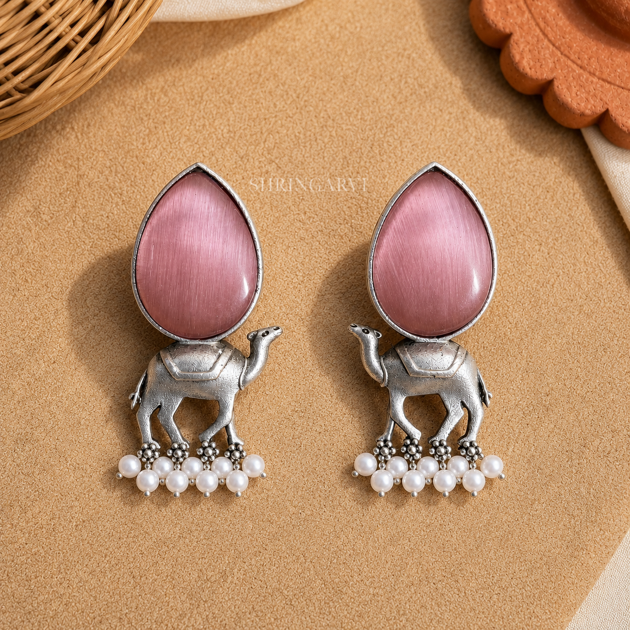 Handcrafted Blush Pink Monalisa Camel Danglers in oxidised brass featuring teardrop Blush Pink Monalisa stones, detailed camel motifs, and pearl drop accents for festive and ethnic styling.