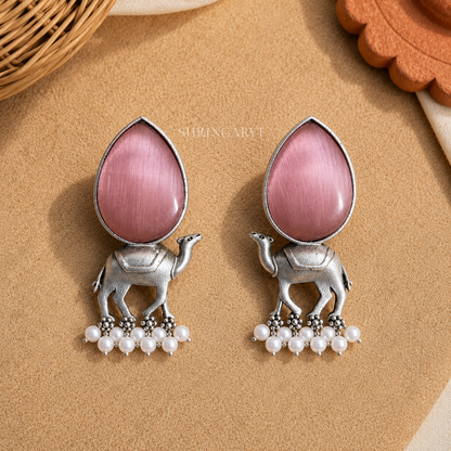 Handcrafted Blush Pink Monalisa Camel Danglers in oxidised brass featuring teardrop Blush Pink Monalisa stones, detailed camel motifs, and pearl drop accents for festive and ethnic styling.