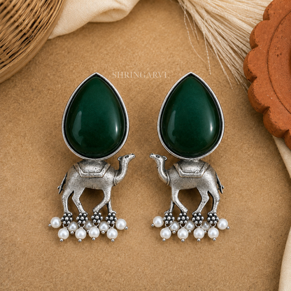 Handcrafted Emerald Green Monalisa Camel Danglers in oxidised brass featuring teardrop Monalisa stones, detailed camel motifs, and pearl drop accents for festive and ethnic styling.