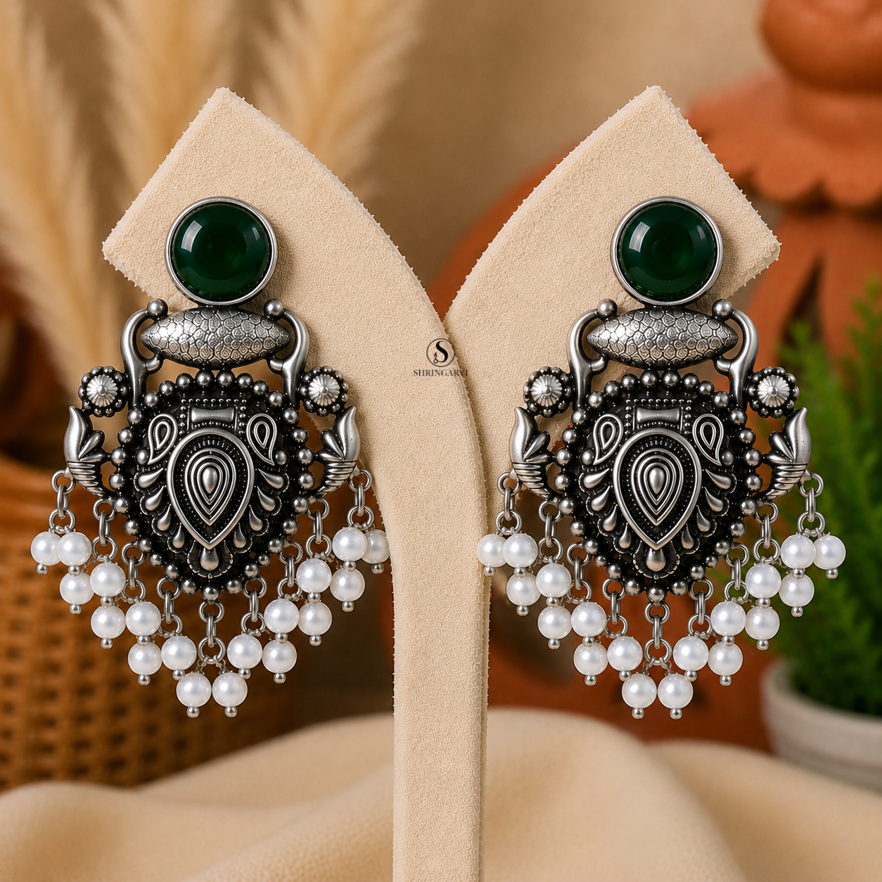 Handcrafted Emerald Green Raagini Danglers in oxidised brass featuring emerald green stones, intricate traditional motifs, and elegant pearl drop accents for festive and ethnic styling.