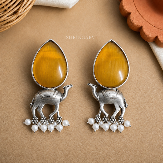 Handcrafted Golden Yellow Monalisa Camel Danglers in oxidised brass featuring teardrop Monalisa stones, detailed camel motifs, and pearl drop accents for festive and ethnic styling.