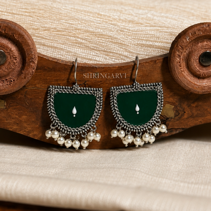Handcrafted Green Bindu oxidised brass danglers featuring green Meenakari enamel detailing, intricate oxidised border, and pearl drop accents for festive and ethnic styling.