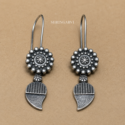 Gulika Mini Danglers in oxidised brass featuring floral stud tops and textured leaf-shaped dangling charms on a white background.