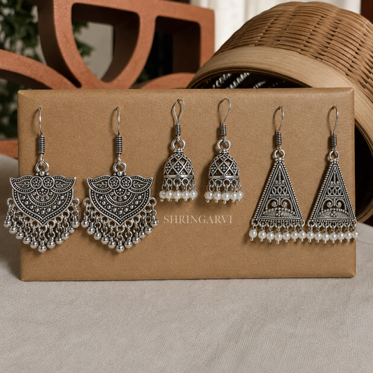 A set of three oxidised Indian jhumka earrings with intricate filigree work and white pearl bead drops