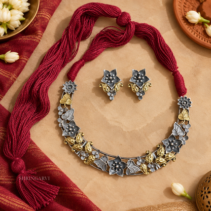 Juhi Dual Tone Floral Necklace Set in brass with oxidised silver and antique gold finish, floral motifs, maroon thread necklace, and matching earrings for festive and ethnic wear.