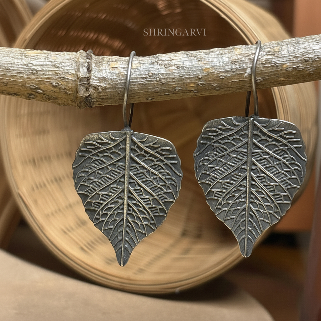 Peepal leaf inspired handcrafted oxidised brass danglers with intricate engraved detailing.