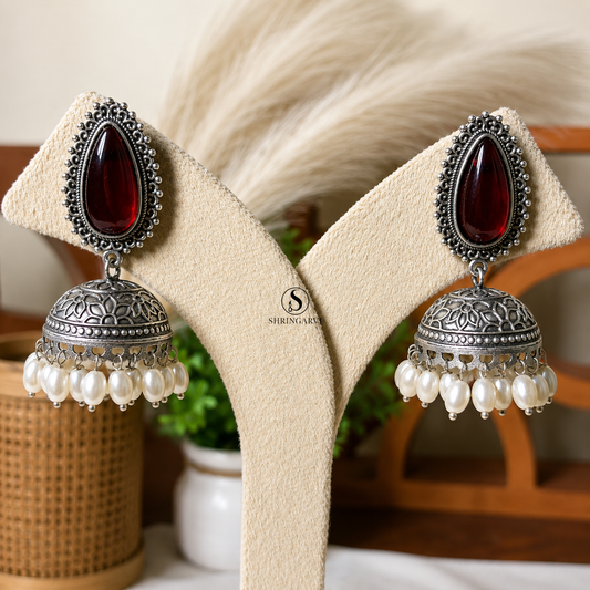 Red Gaura oxidised silver jhumka earrings with red teardrop stone and pearl drop accents.