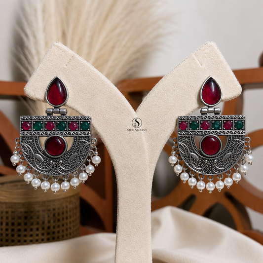 Ruby Green Aadya Chandbalis handcrafted in oxidised brass featuring ruby and emerald green stones, intricate traditional detailing, and pearl accents for festive and ethnic wear.