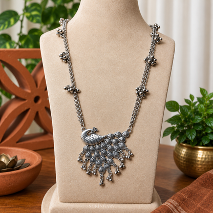 Oxidized silver peacock necklace for women, handcrafted tribal statement necklace with ghungroo detailing, long ethnic necklace styled with traditional Navratri Garba outfit.