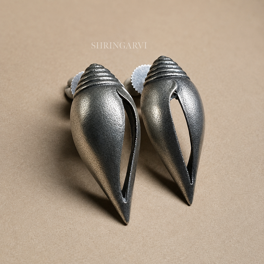 Tarangini conch inspired oxidised brass stud earrings with sculptural spiral design.
